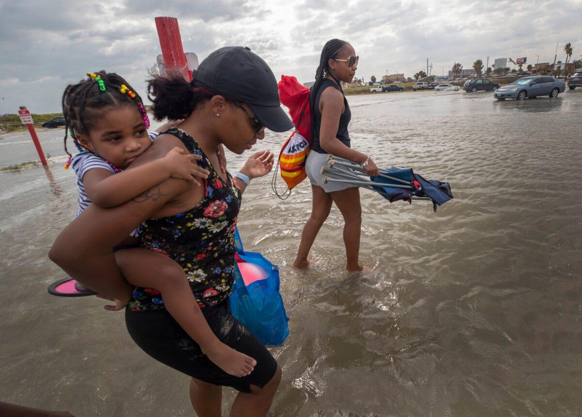 Stacey Young gives her daughter, Kylee Potts, a piggyback ride across the flooding Stewart Beach parking lot in Galveston, Texas, on Sept. 19, 2020. (Stuart Villanueva/The Galveston County Daily News via AP)