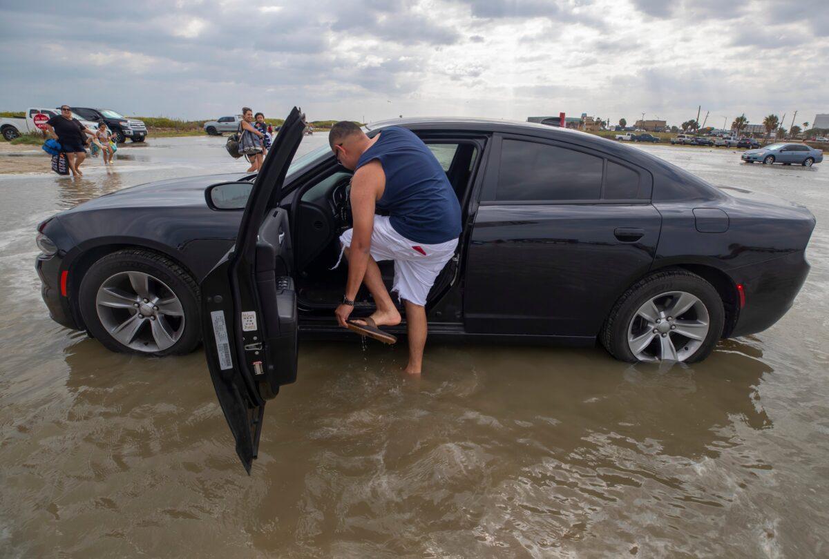 Houston resident Lupe Don removes his flip-flops while moving his car from the flooding Stewart Beach parking lot in Galveston, Texas, on Sept. 19, 2020. (Stuart Villanueva/The Galveston County Daily News via AP)