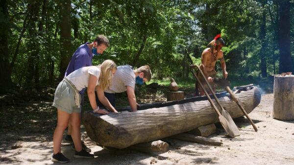 Masked visitors explore a dug-out canoe at the Jamestown Settlement, which has reopened after the shutdown. (Jamestown-Yorktown Foundation)