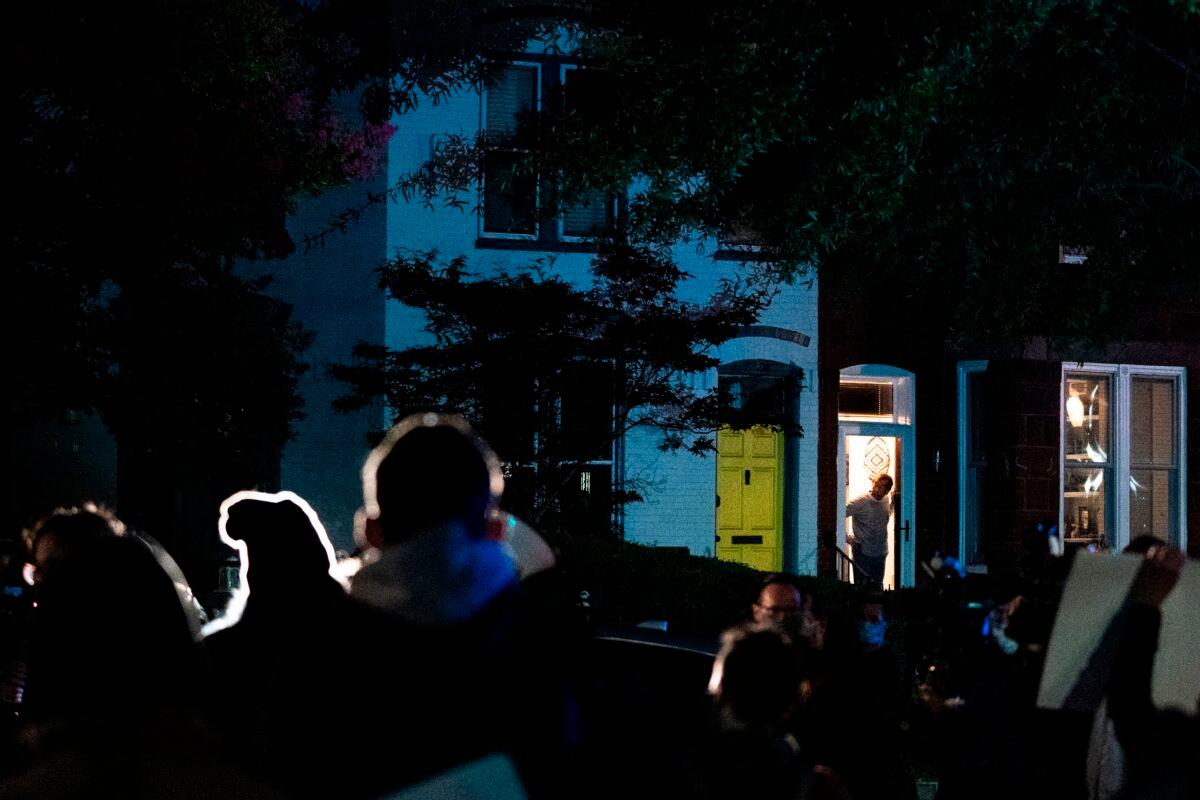 A neighbor looks out their door at demonstrators outside the home of Sen. Lindsey Graham (R-S.C.) in Washington on Sept. 21, 2020. (Alex Edelman/AFP via Getty Images)