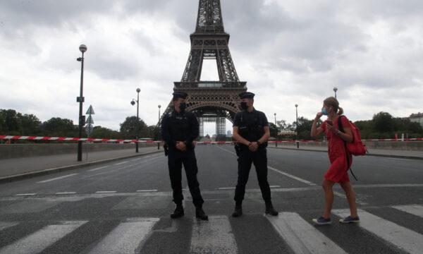  A woman walks past police officers securing the bridge leading to the Eiffel Tower in Paris, on Sept. 23, 2020. (Michel Euler/AP Photo)
