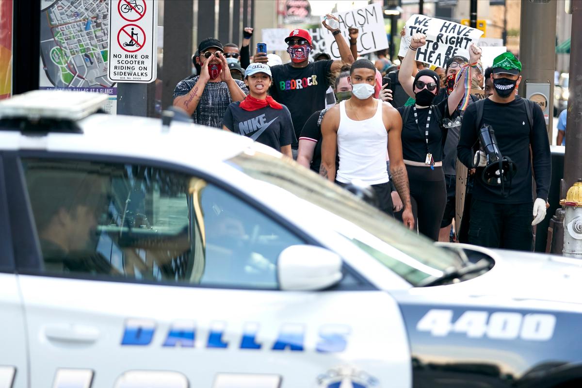  Demonstrators march near a Dallas police car during a protest against police brutality and racism in Dallas, Texas, on June 6, 2020. (Cooper Neill/Getty Images)