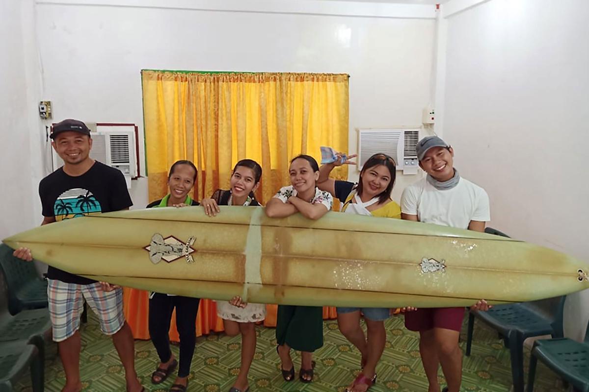 This undated handout photo received on Sept. 18, 2020, courtesy of Giovanne Branzuela shows Filipino teacher Giovanne Branzuela (L) posing with his surfboard, once owned by big-wave surfer Doug Falter, who lost it while surfing in Hawaii, along with his village mates on Sarangani island in the Philippines. (Giovanne Branzuela/Handout/AFP/Getty Images)
