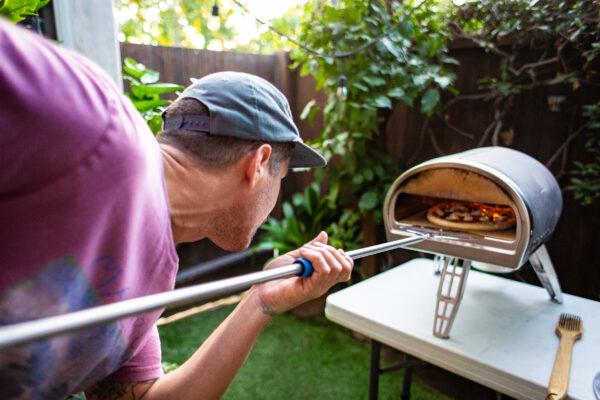Landon Pietrini cooks pizza in a portable pizza oven in Seal Beach, Calif., on Sept. 19, 2020. (John Fredricks/The Epoch Times)
