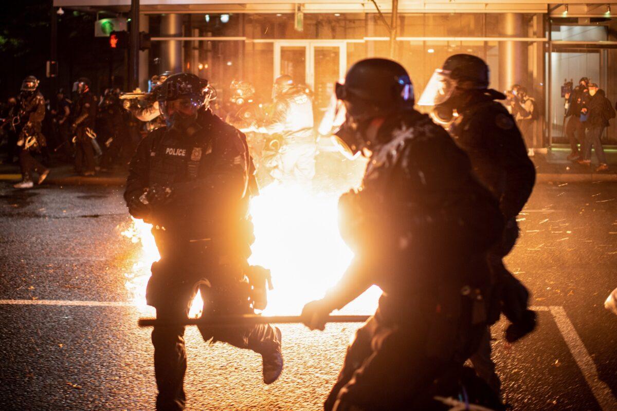 Portland police officers evade a Molotov cocktail amid rioting in Portland, Ore. (Mathieu Lewis-Rolland/Reuters)
