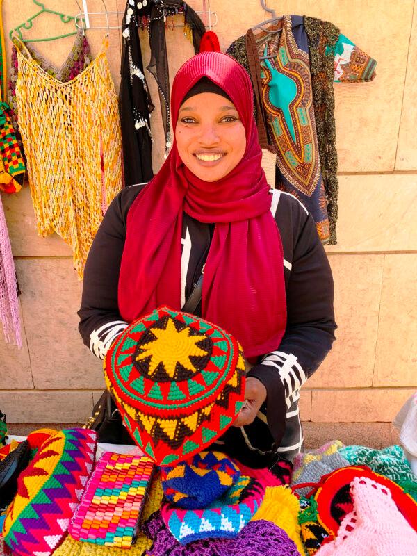 A Nubian woman displaced from her homeland by the building of the Aswan High Dam and the flooding of Lake Nasser displays her handmade artwork and crafts. (Courtesy of Phil Allen)