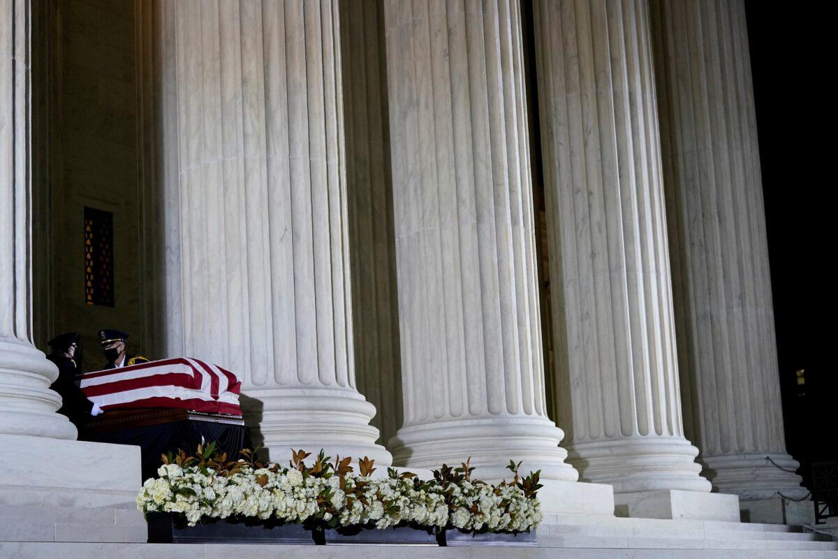 A Supreme Court Honor Guard salutes before moving the flag-draped casket of Justice Ruth Bader Ginsburg back into the court as Ginsburg lies in repose under the Portico at the top of the front steps of the Supreme Court building in Washington on Sept. 24, 2020. (Andrew Harnik/Pool via Reuters)