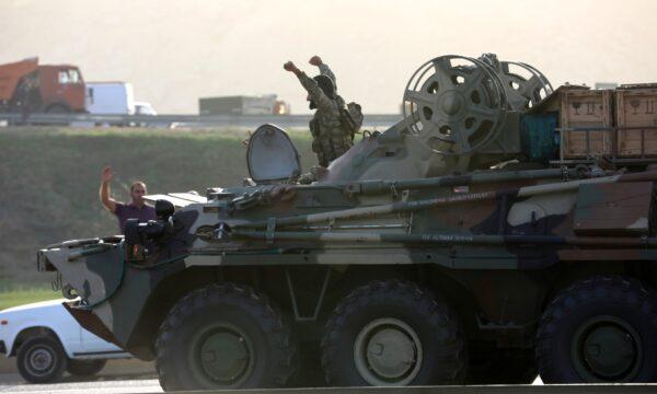 An Azerbaijani service member drives an armored carrier and greets people, who gather on the roadside in Baku, Azerbaijan, on Sept. 27, 2020. (Aziz Karimov/Reuters)