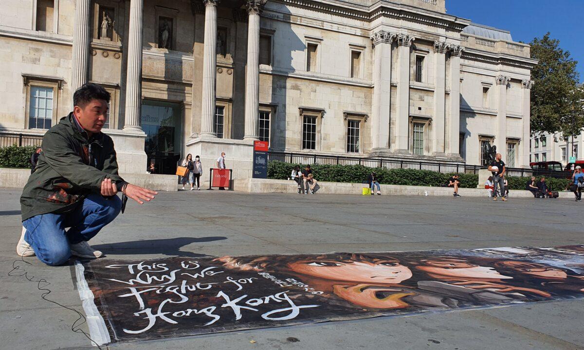 Otto Yuen tells stories behind his 10-meter painting about Hong Kong's pro-democracy movement, in Trafalgar Square, London, on Sept. 21, 2020. (Lily Zhou/The Epoch Times)