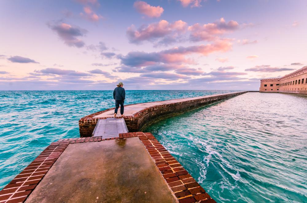A man takes a walk around the moat at Fort Jefferson. (Sandra Foyt/Shutterstock)