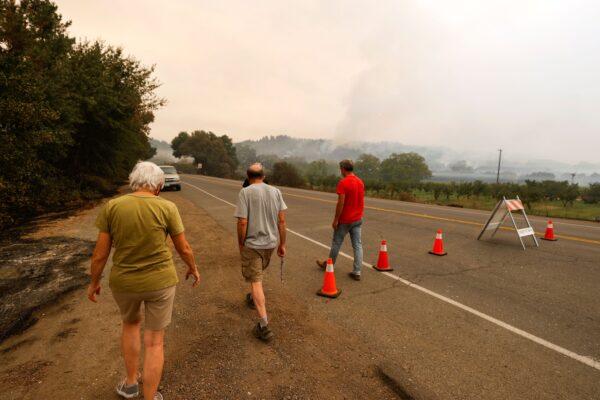 Evacuated residents Esther Brunswick, her husband Ron Brunswick, and Chris Hale walk away from a police checkpoint after trying to check on their homes, in Deer Park, Calif., on Sept. 28, 2020. (Fred Greaves/Reuters)