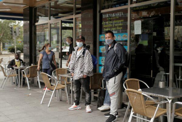 People wearing protective face masks stand outside a restaurant at Usera neighbourhood, amid the outbreak of the coronavirus disease (COVID-19) in Madrid, Spain, on Sept. 19, 2020. (Javier Barbancho/Reuters)