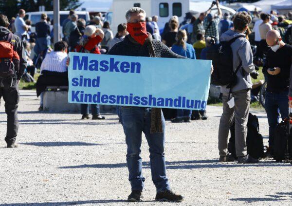A man displays a poster reading: "Masks are child abuse" during a protest against the government's restrictions, in Konstanz, Germany, on Oct. 4, 2020. (Arnd Wiegmann/Reuters)