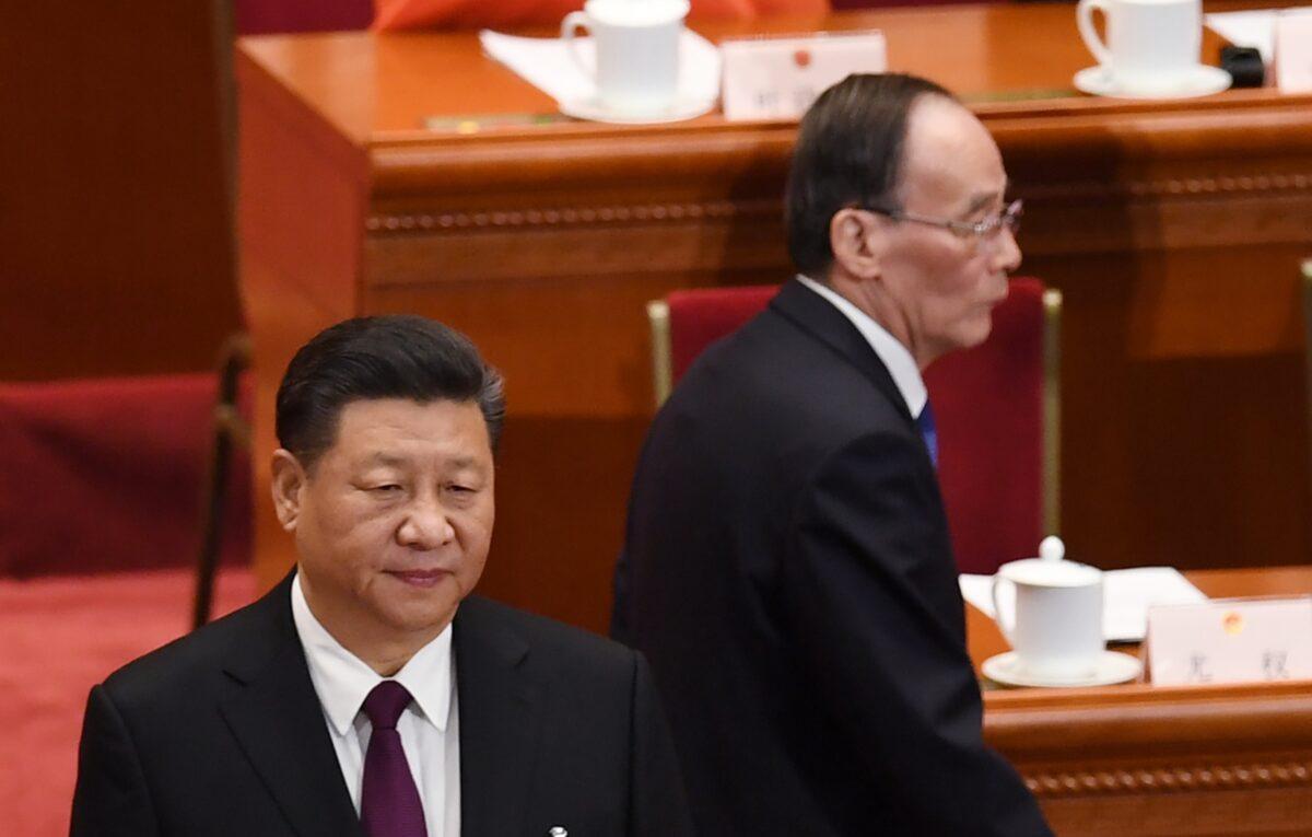 China's leader Xi Jinping (left) stands as Wang Qishan (right), former secretary of the Central Commission for Discipline Inspection, arrives for the CCP’s first session of the 13th National People's Congress in Beijing, China, on March 17, 2018. (Greg Baker/AFP via Getty Images)