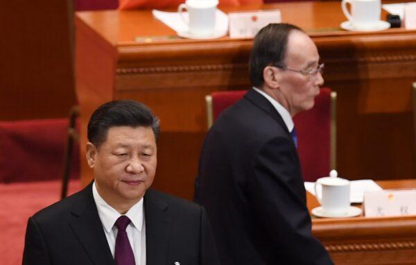 China's leader Xi Jinping (L) stands as Wang Qishan (R), former secretary of the Central Commission for Discipline Inspection, arrives for the CCP’s first session of the 13th National People's Congress in Beijing, on March 17, 2018. (GREG BAKER/AFP via Getty Images)