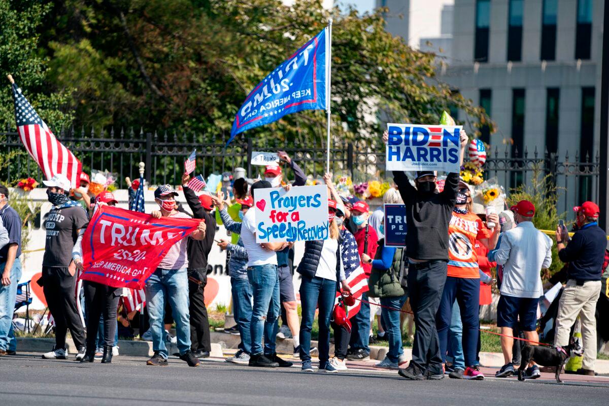 A supporter of Joe Biden and Sen. Kamala Harris (D-Calif.) holds a sign amid a crowd of President Donald Trump supporters, outside of Walter Reed Medical Center in Bethesda, Md., Oct. 4, 2020. (Alex Edelman/AFP via Getty Images)