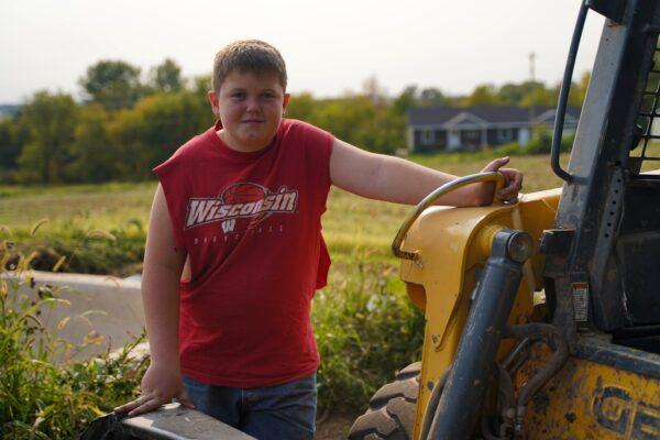 Dairy farmer Cary Moser can't afford to hire workers on his farm, so he runs it himself; but his grandson helps him after school each day. (Cara Ding/The Epoch Times)