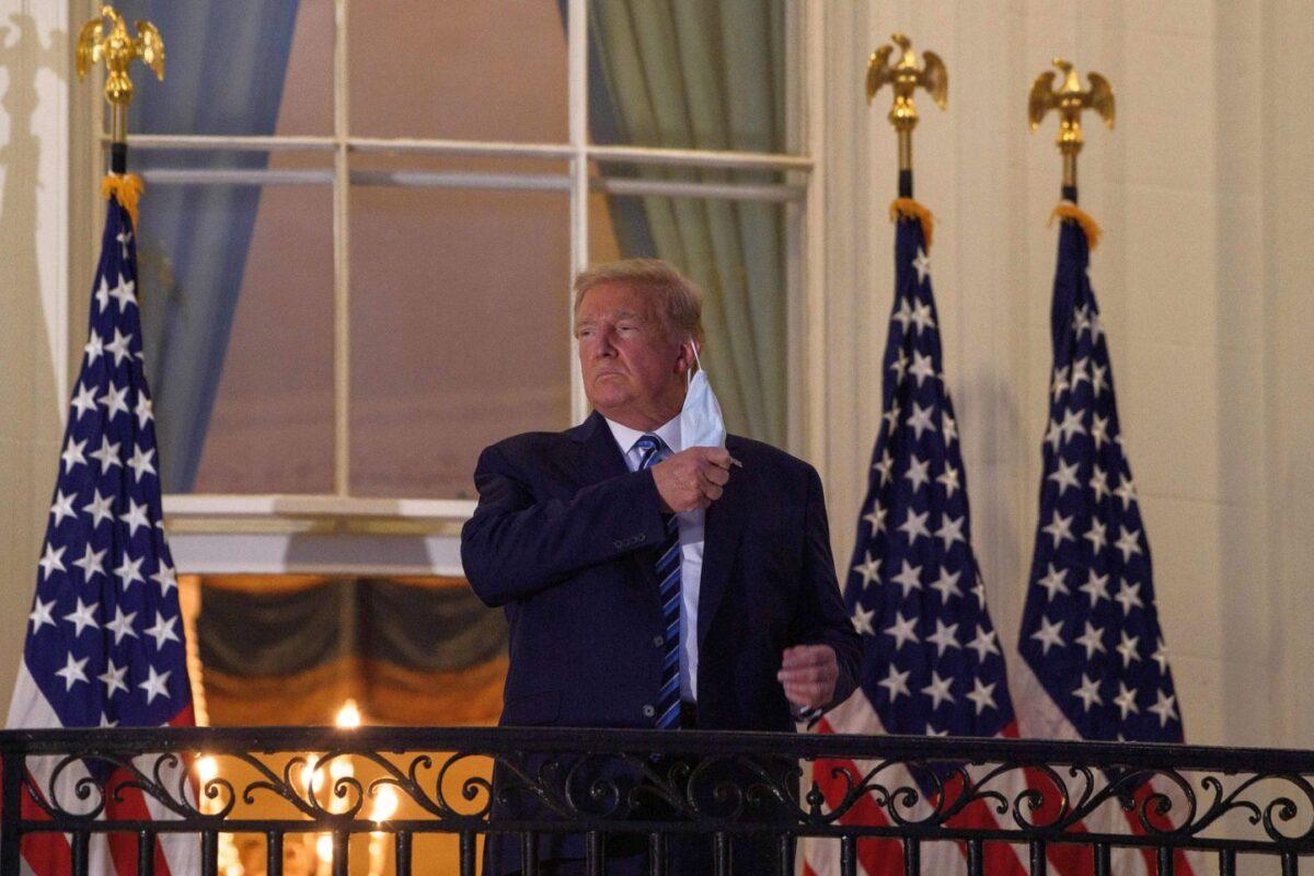 President Donald Trump takes off his mask as he arrives at the White House upon his return from Walter Reed Medical Center, where he underwent treatment for the CCP virus, in Washington on Oct. 5, 2020. (Nicholas Kamm/AFP via Getty Images)