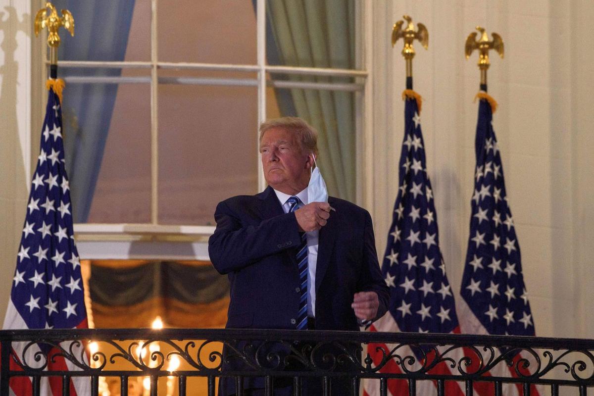 President Donald Trump takes off his facemask as he arrives at the White House upon his return from Walter Reed Medical Center, where he underwent treatment for COVID-19, in Washington, on Oct. 5, 2020. (Nicholas Kamm/AFP)
