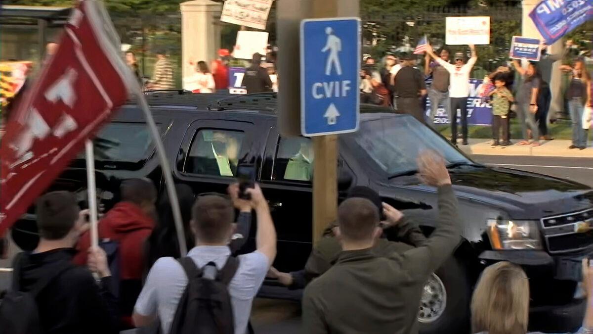 In this image from video, President Donald Trump waves as he drives past supporters gathered outside Walter Reed National Military Medical Center in Bethesda, Md., Oct. 4, 2020. (Carlos Vargas/AP Photo)