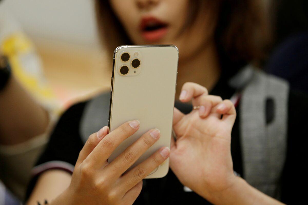 A woman holds an iPhone 11 Pro Max while giving a live broadcast after it went on sale at the Apple Store in Beijing, China, on Sept. 20, 2019. (Jason Lee/Reuters)