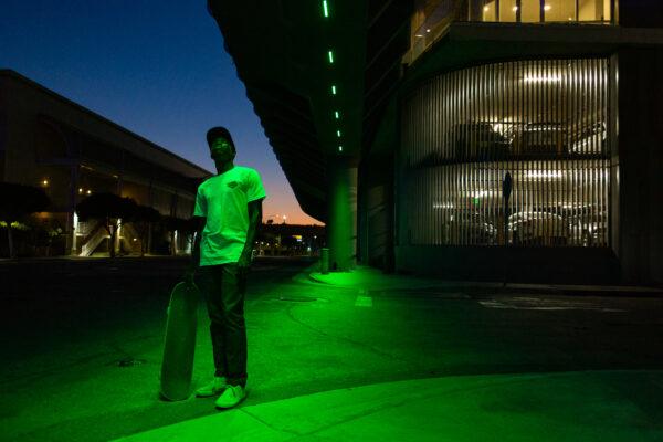 Skateboarder Kwami Adzitso stands with his board in Long Beach, Calif., on Sept. 23, 2020. After working his day job in insurance, his evenings are skate time. (John Fredricks/The Epoch Times)