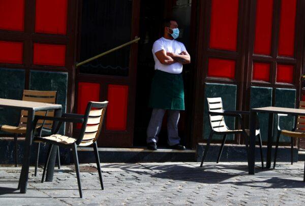 A waiter wearing a protective face mask waits for customers in his terrace amid the outbreak of the coronavirus disease (COVID-19), in Madrid, on Oct. 1, 2020. (Sergio Perez/Reuters)