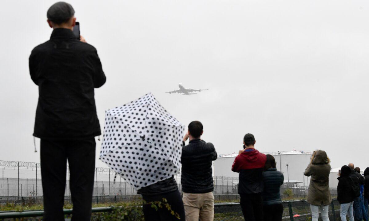 Spectators take images of a British Airways Boeing 747 as it does a flypast over London Heathrow airport on its final flight, the last of 31 jumbo jets to be retired early by the airline due to the coronavirus disease (COVID-19) pandemic, in London, Britain, on Oct. 8, 2020. (Toby Melville/Reuters)