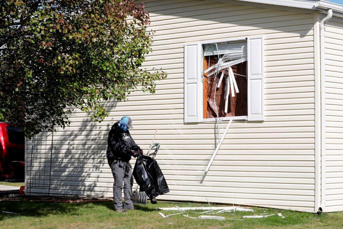 A person cleans up debris from a broken window at a home FBI agents searched in Hartland Township mobile home park late Wednesday night and into Thursday morning in connection to an alleged plot to kidnap Michigan Gov. Gretchen Whitmer, in Heartland, Mich., Oct. 8, 2020. (Jeff Kowalsky/AFP via Getty Images)