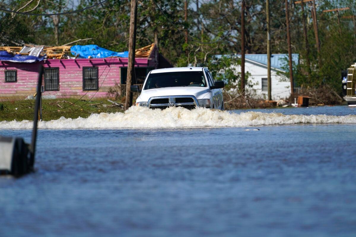 A truck drives through a flooded street in Lake Charles, La., on Oct. 10, 2020, past a home with damage from Hurricane Laura. (Gerald Herbert/AP Photo)