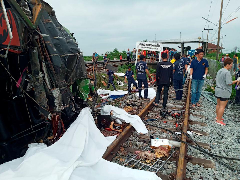 Rescue workers stand at the crash site where a train collided with a paseengers bus in Chacheongsao province in central Thailand on Oct.11, 2020.(Dailynews via Reuters)