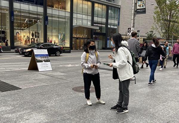 A Chinese lady listens as the volunteer explains to her the purpose of the petition in Toronto on Oct. 10, 2020. (Dongyu Teng/The Epoch Times)