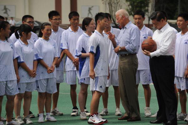 Then-U.S. Vice President Joe Biden (C-R) talks with a student as Chinese Vice President Xi Jinping (R) signs a basketball at Dujiangyan Qingchengshan high school outside Chengdu in China's southwest province of Sichuan on Aug. 21, 2011. (PETER PARKS/AFP via Getty Images)