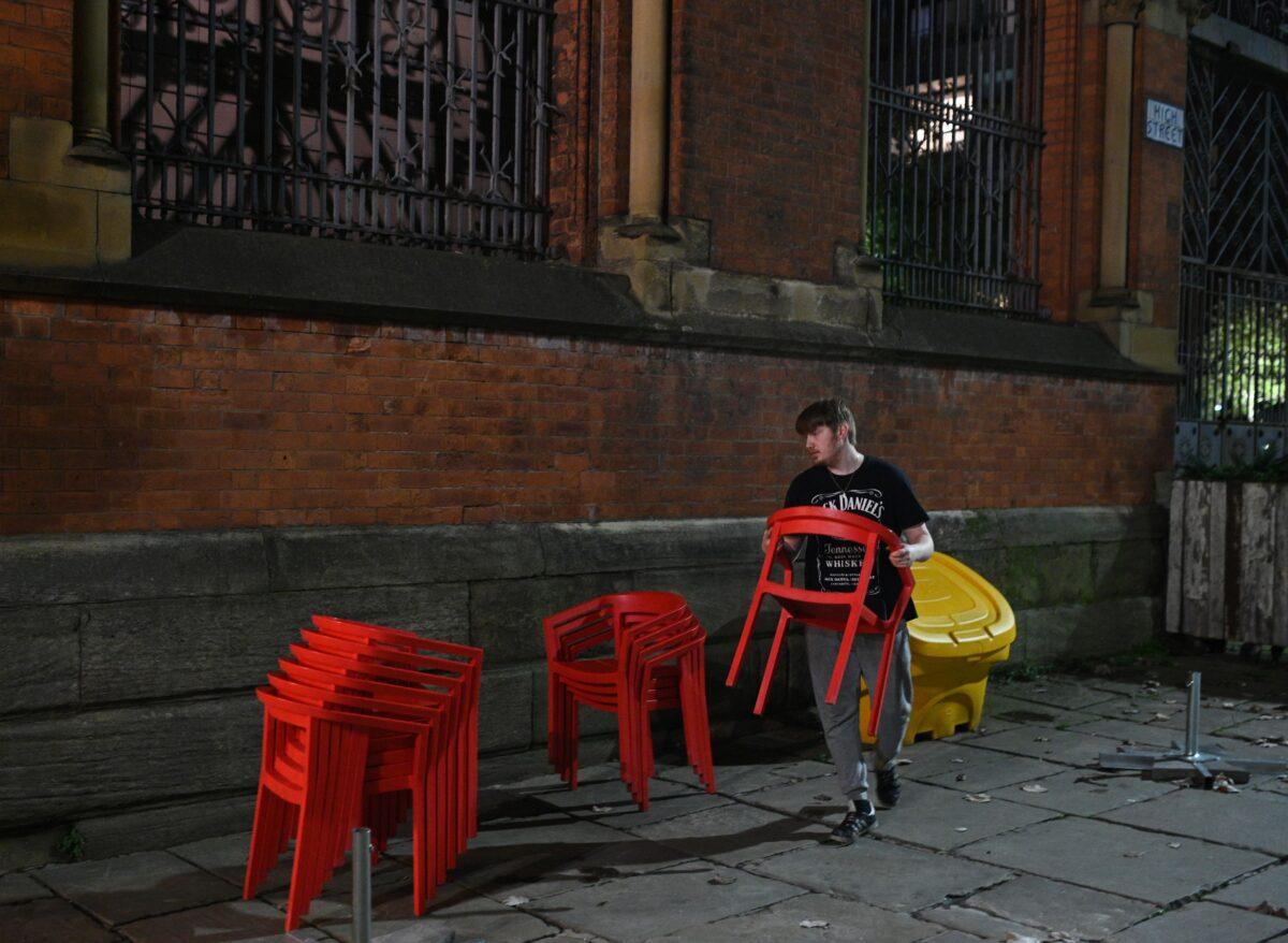 A member of staff clears away chairs outside a bar in the city center of Manchester, England, on Oct. 8, 2020. (Oli Scarff/AFP via Getty Images)