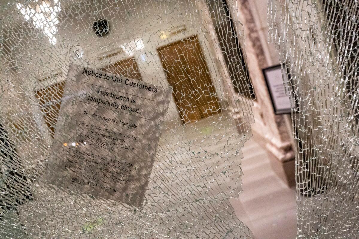 A sign informing visitors of a temporary bank branch closure hangs from a window broken during a riot in Portland, Ore., Oct. 11, 2020. (Nathan Howard/Getty Images)