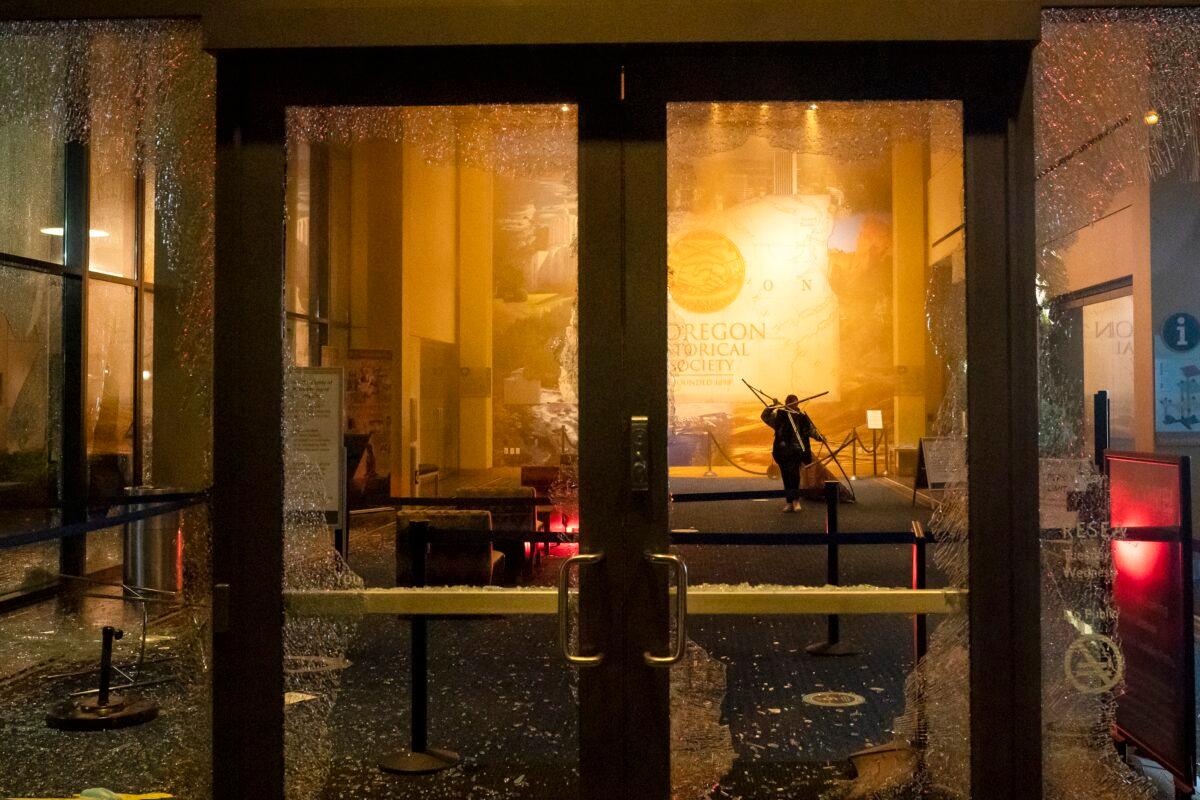A woman pulls a quilt from the display case inside the Oregon Historical Society during a riot in Portland, Ore., Oct. 11, 2020. (Nathan Howard/Getty Images)