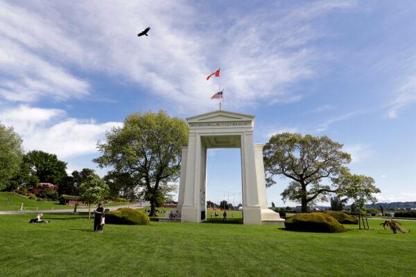 In this photo taken Sunday, May 17, 2020, a bird flies from the U.S. into Canada over the Peace Arch in Peace Arch Historical State Park on the border with Canada, where people can walk freely between the two countries at an otherwise closed border, in Blaine, Wash. (AP Photo/Elaine Thompson)