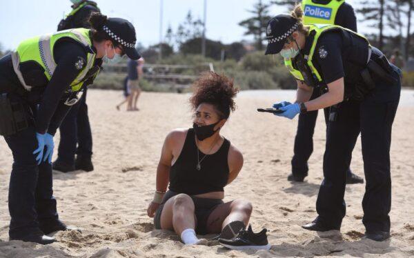 Police surround a protester as they detain her on Elwood Beach in Melbourne on Sept. 19, 2020. (William West /AFP via Getty Images)