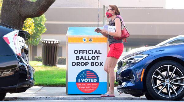 A woman holding her ballot walks past a Vote by Mail Drop Box for the 2020 U.S. Elections in Monterey Park, Calif., on Oct. 5, 2020. (Frederic Brown/AFP via Getty Images)