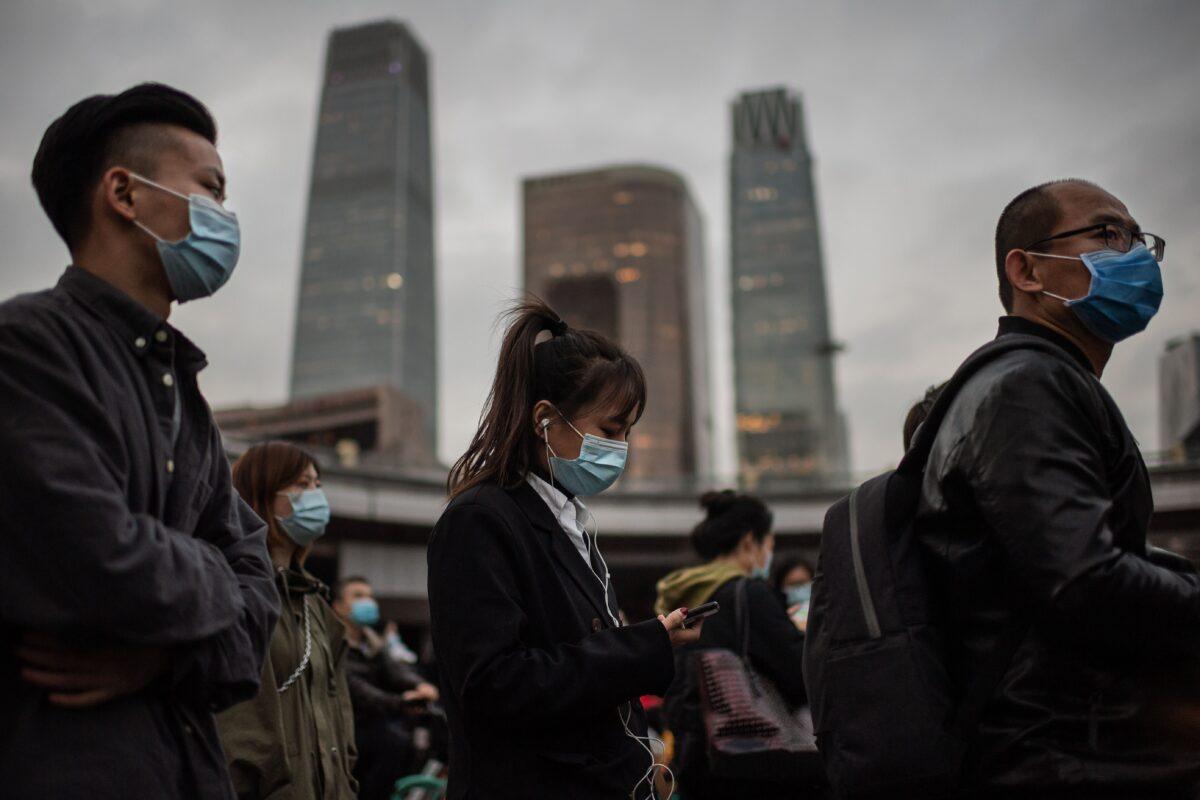 People wearing face masks as a preventive measure against the Covid-19 coronavirus wait at a red light to cross a street during rush hour in Beijing on Oct. 14, 2020. (Nicolas Asfouri/AFP via Getty Images)