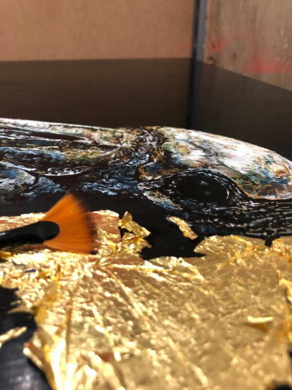 Andrew Pledge gently embellishes the neck of his wood stork painting with gold leaf. (Courtesy of Andrew Pledge)
