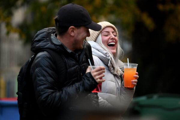 A couple drink from takeaway glasses outside a pub in the Grassmarket following last orders at 6 p.m. in Edinburgh, Scotland, on Oct. 9, 2020. (Jeff J Mitchell/Getty Images)