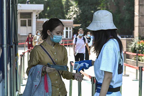 A student (L) has her body temperature checked before entering a school to sit the National College Entrance Examination (NCEE), known as Gaokao, in Nanjing, in China's eastern Jiangsu province on July 7, 2020. (STR/AFP via Getty Images)
