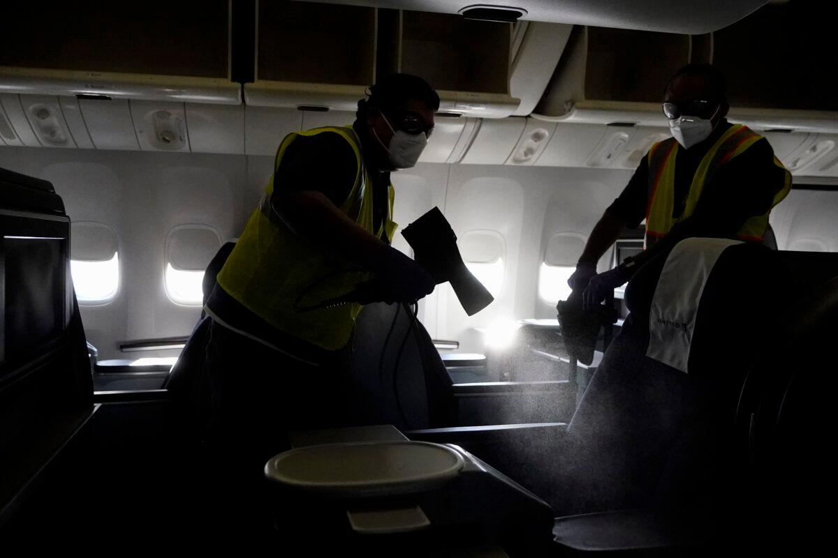Workers with ABM Industries give a demonstration on cleaning inside a United Airlines plane destined for Hawaii at San Francisco International Airport in San Francisco, Calif., Oct. 15, 2020. (Jeff Chiu/AP Photo)