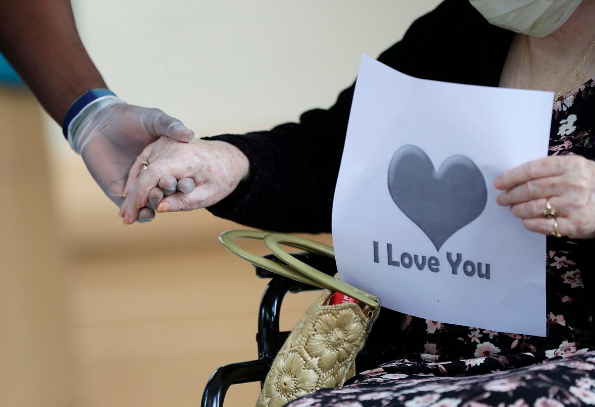 A senior citizen holds the hand of a care coordinator at a Health facility in Miami, Fla., on July 17, 2020. (Wilfredo Lee/AP Photo)
