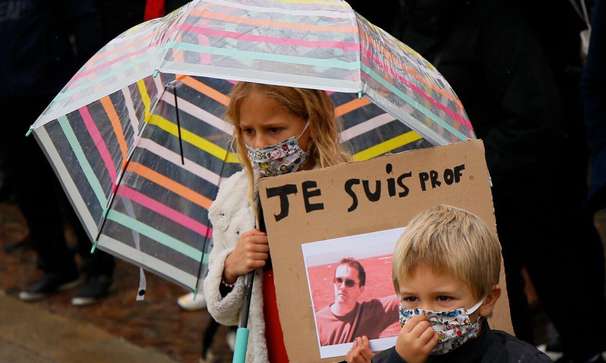 A child holds up a poster of Samuel Paty as people gather on Republique square in Lille, northern France, on Oct. 18, 2020. Demonstrators in France took part in gatherings in support of freedom of speech and in tribute to the history teacher who was beheaded near Paris after discussing Mohammad cartoons with his class. (Michel Spingler/AP Photo)