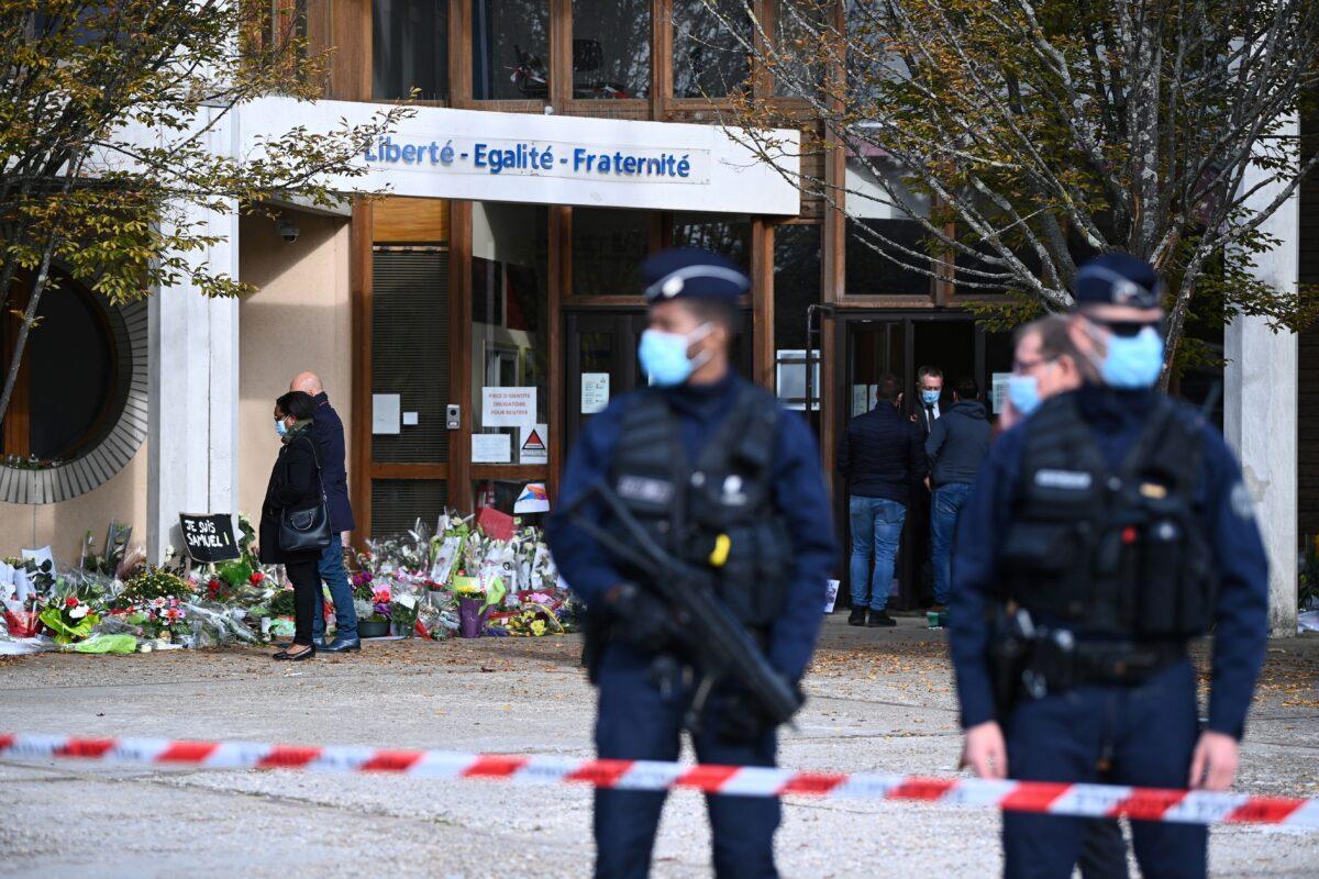 People look at flowers laid in homage to slain history teacher Samuel Paty, outside the Bois d'Aulne secondary school, in Conflans-Sainte-Honorine, northwest of Paris, on Oct. 19, 2020. (Anne-Christine Poujoulat/AFP via Getty Images)