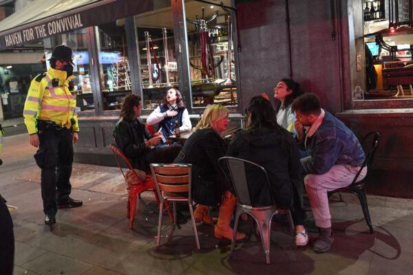 A police officer speaks to people sitting outside a pub in Soho, London, on Sept. 24, 2020. (Peter Summers/Getty Images)
