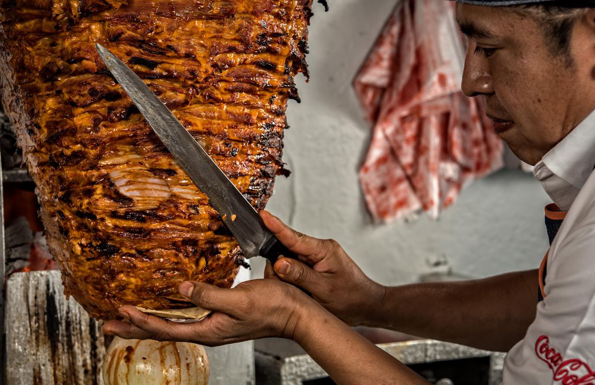 Chef Adrian Reyes cuts small slices of marinated thin fillets of pork already cooked from "the ball" or "the spinning top" to make traditional tacos al pastor" (shepherd-style tacos) at El Tizoncito restaurant in Mexico City, on Oct. 31, 2016. (OMAR TORRES/AFP via Getty Images)