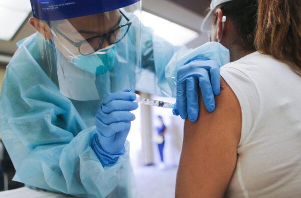 A nurse administers a flu vaccination shot to a woman at a free clinic held at a local library on October 14, 2020, in Lakewood, California. (Mario Tama/Getty Images)